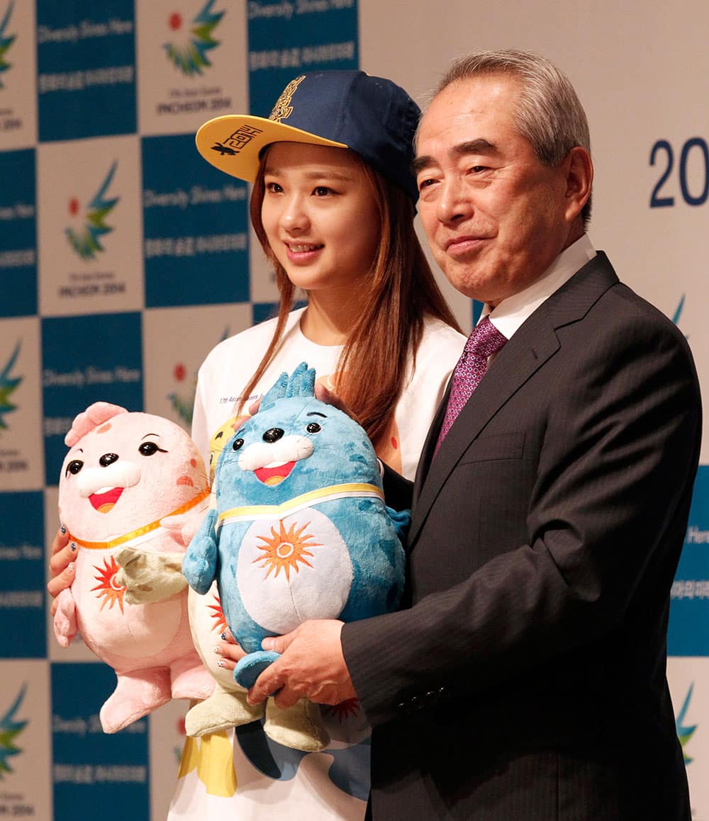 South Korean rhythmic gymnast Son Yeon-jae, left, poses with the president of 2014 Incheon Asian Games Organizing Committee Kim Young-soo as they hold three official mascots during a promotional event for the upcoming 17th Asian Games.