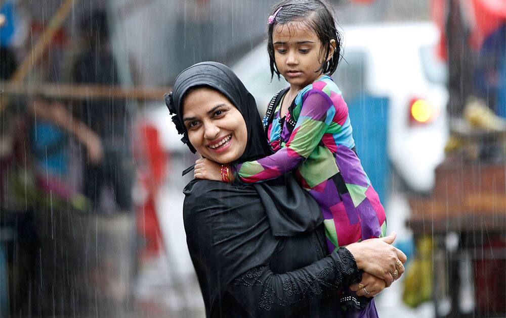 A woman carrying a child reacts to camera as she gets drenched in heavy downpour in Allahabad.