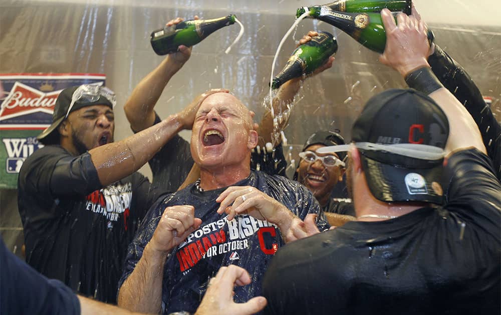 Cleveland Indians third base coach Brad Mills, center, is showered with champagne in the locker room after the Indians beat the Twins 5-1 in a baseball game in Minneapolis.