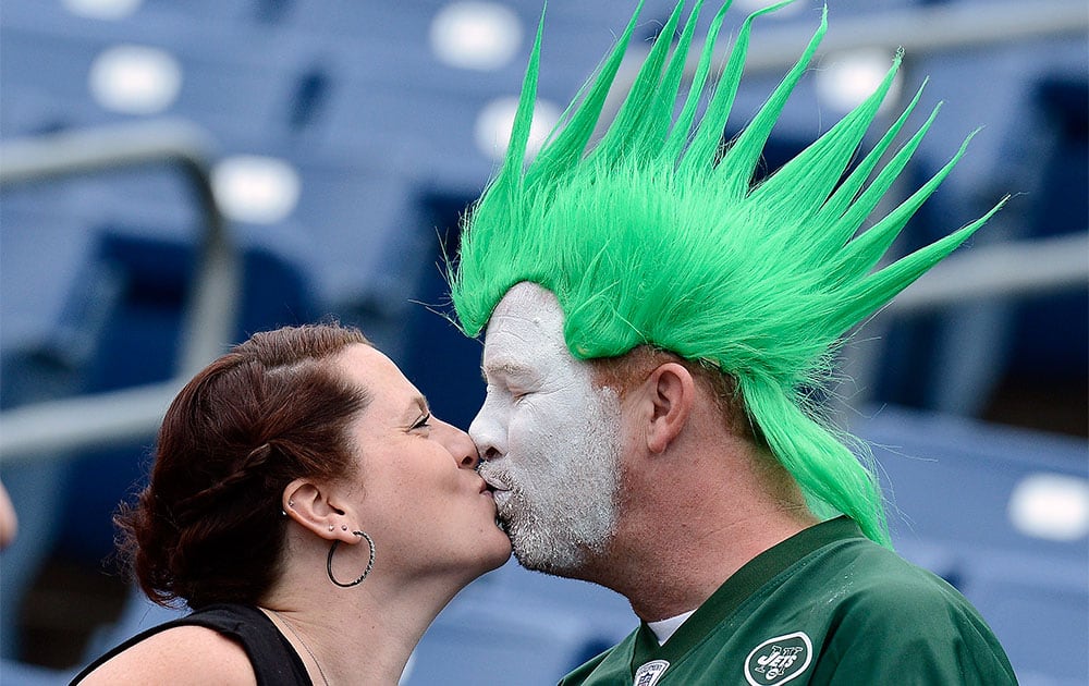 New York Jets fans Ana Hall and Rick Martin kiss as they watch players warm up before an NFL football game between the Jets and the Tennessee Titans in Nashville, Tenn.