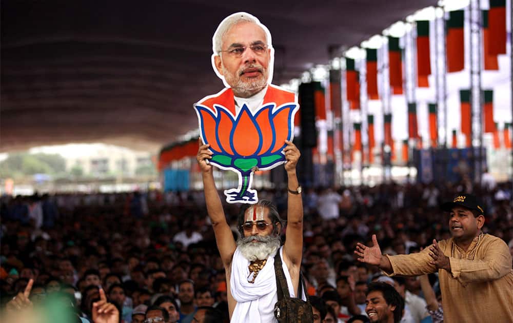 A supporter holds a cut-out photograph of India’s opposition Bharatiya Janata Party (BJP) leader Narendra Modi with the party symbol lotus as he addresses a public rally in New Delhi.