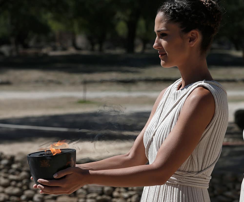 An actress in the role of a priestess carries the flame from the temple of Hera to the ancient Olympic Stadium, during the lighting of the Olympic flame at Ancient Olympia, in west southern Greece.