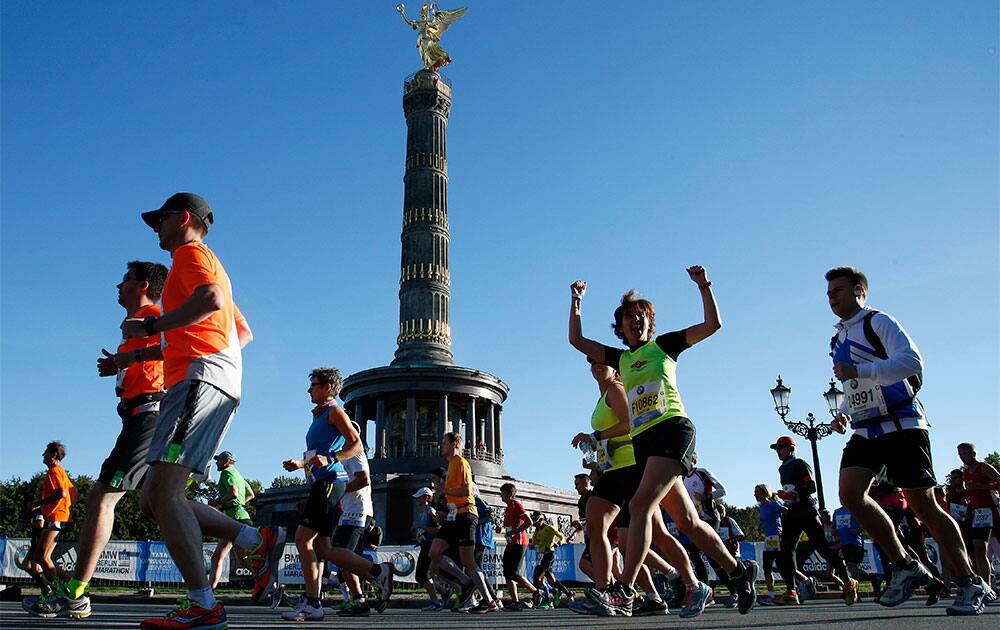 A runner raises her arms in front of the victory column just after the start of the 40th Berlin Marathon in front of the Brandenburg Gate in Berlin, Germany. Some 40,000 runners take part in the event.