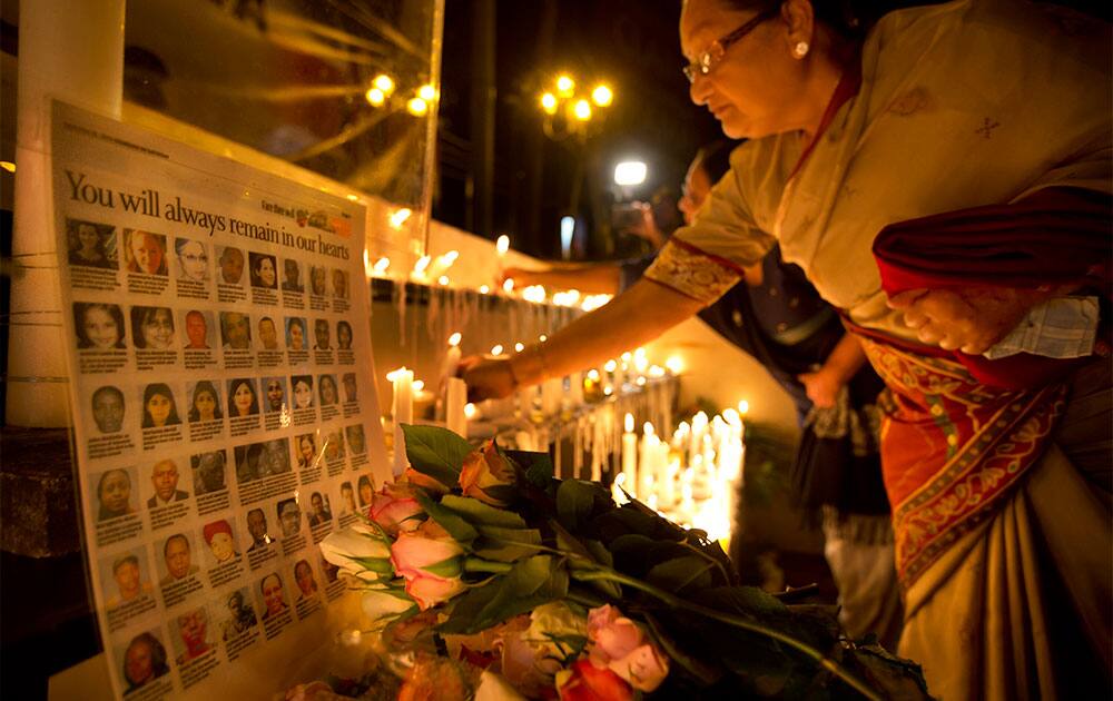 A woman lights a candle next to a list of the names of those who died, as Kenyans came together to mark one week since the terrorist attack that killed 67 people, by laying flowers, praying and lighting candles to pay their respects, in front of the Westgate Mall in Nairobi.