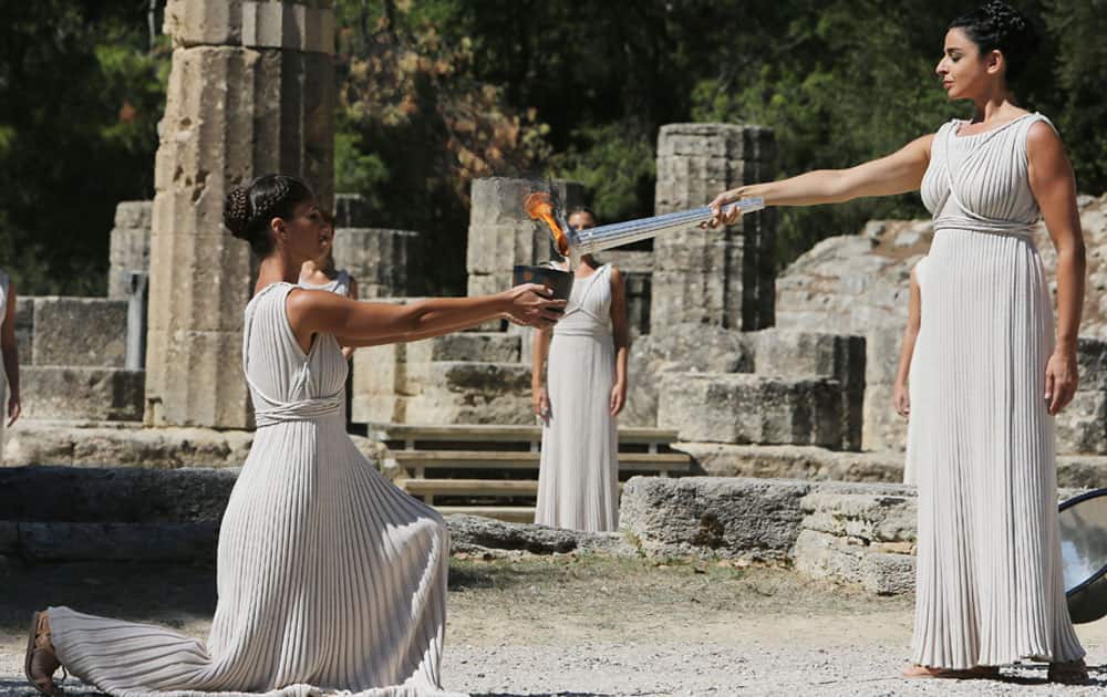 Actress Ino Menegaki as high priestess, right, passes the Olympic Flame to a priestess after it was lit from the sun`s rays, during the final dress rehearsal for lighting of the Olympic flame at Ancient Olympia.