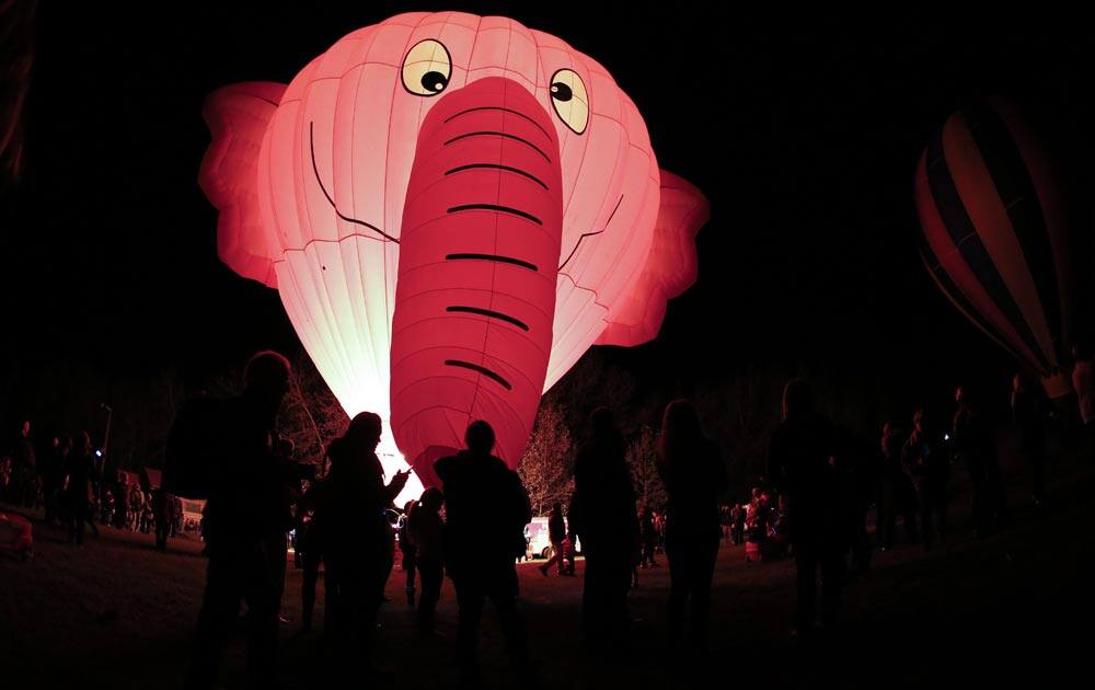 Onlookers watch an elephant shaped hot air balloon glow at sunset during a kick off event for the Canadian Hot Air Balloon Championships in High River, Altberta.