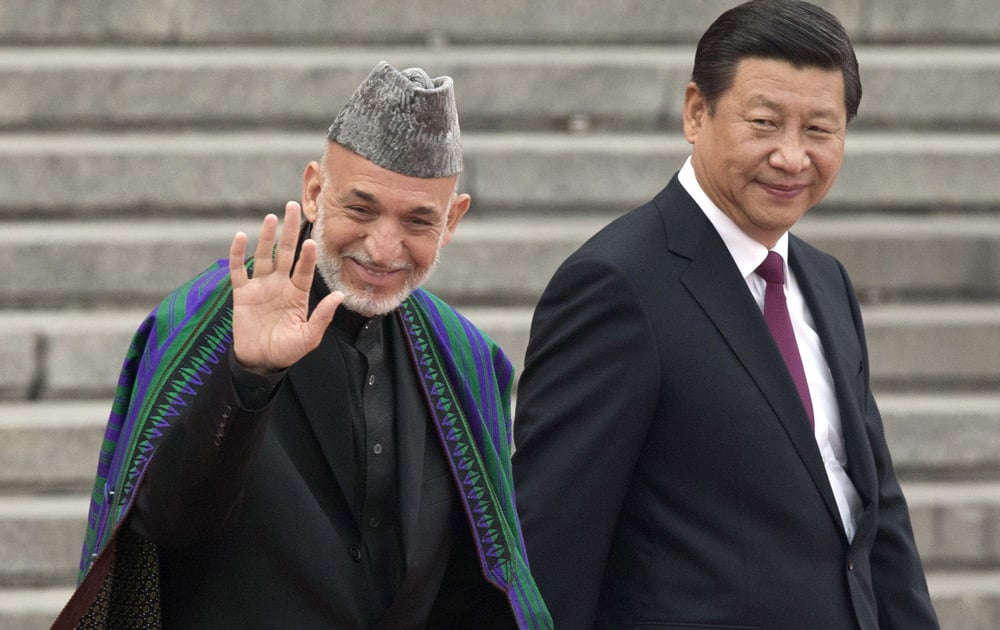 Afghan President Hamid Karzai gestures to Chinese children who are waving flowers and national flags as he walks with Chinese President Xi Jinping during a welcome ceremony outside the Great Hall of the People in Beijing.
