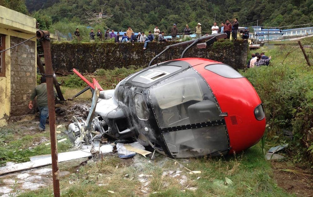 Nepalese look at a helicopter that crashed in Lukla, Nepal. The helicopter crashed while attempting to land near Mount Everest on Thursday, injuring all four people on board, Nepalese police said.