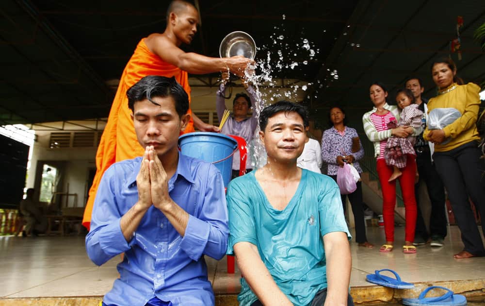 Born Samnang and Sok Sam Oeun are blessed with holly water by a Buddhist monk at a Buddhist pagoda after their release from a main prison in Prey Sar, on the outskirts of Phnom Penh, Cambodia.