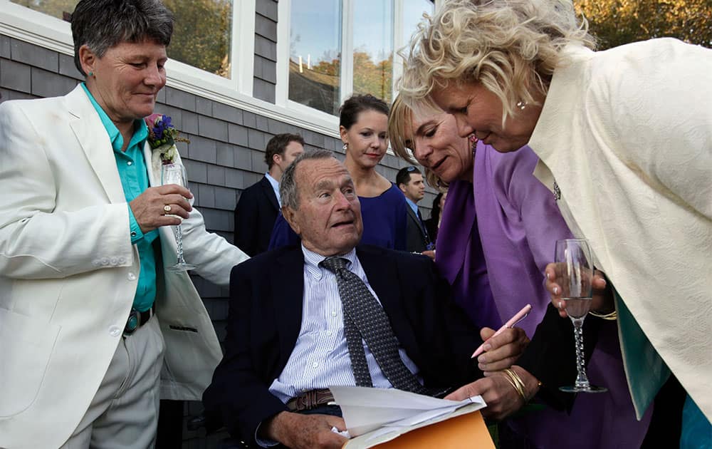 Former President George H.W. Bush, seated center, prepares to sign the marriage license of longtime friends Helen Thorgalsen, right, and Bonnie Clement, left, in Kennebunkport, Maine, as officiant Nancy Sosa, third right, and Helen`s daughter Lindsey, rear, look on. Bush was an official witness at the same-sex wedding, his spokesman said.