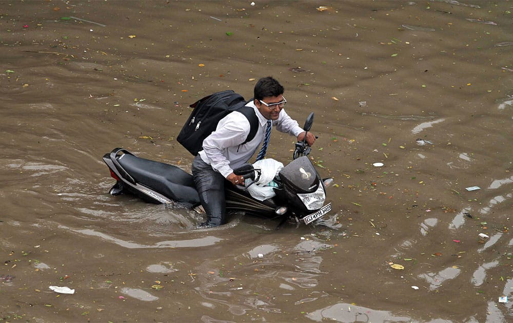 A man pushes his bike through a flooded road after heavy rains in Ahmadabad. Massive flooding has forced 15,000 people to evacuate villages in the west Indian state of Gujarat where heavy rains and swollen rivers have inundated cities and closed off roads and railway lines.