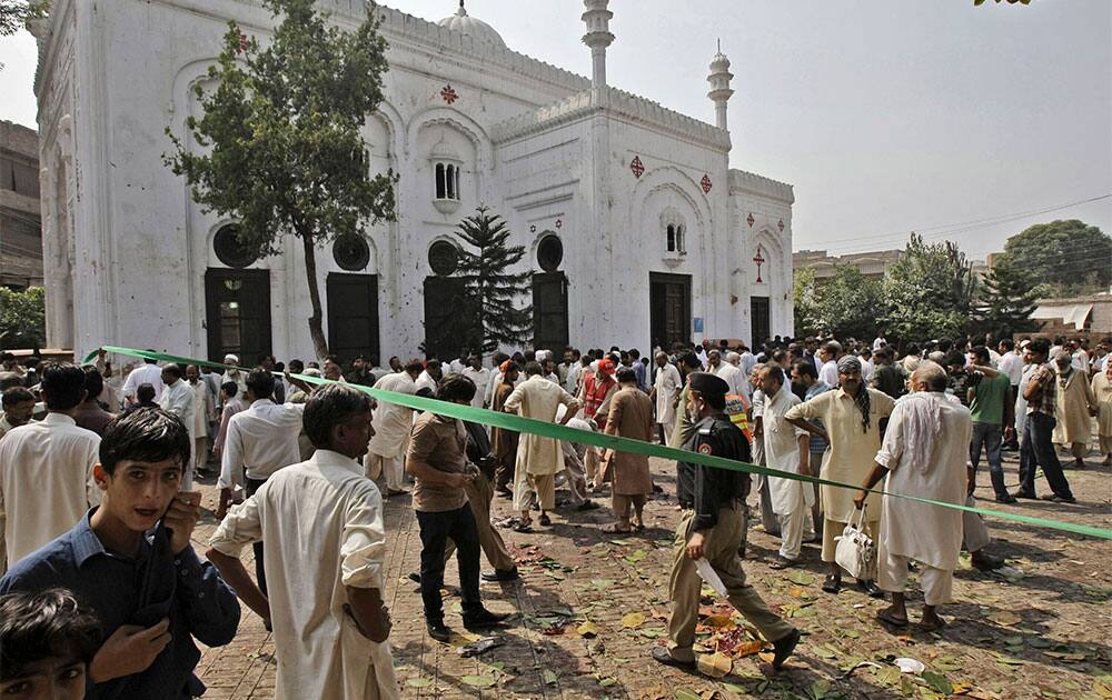 Police officers and civilians, gather at the site of a suicide attack on a church, in Peshawar, Pakistan.