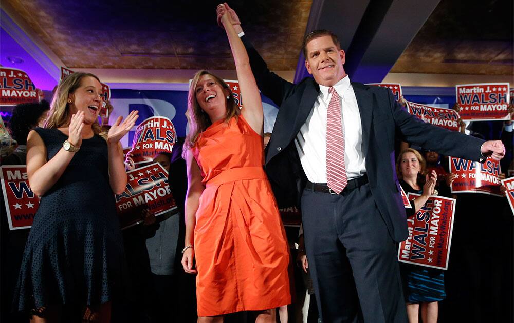 Boston Mayoral hopeful Martin Walsh clasps hands with his girlfriend, Lorrie Higgins, while her daughter Lauren applauds, far left, at his primary election night party in Boston.