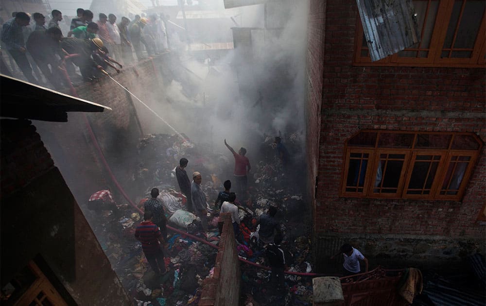 Firefighters and civilians work to extinguish a fire in Srinagar. Three residential houses and a shop were gutted in the fire, according to fire officials. No casualties were reported.
