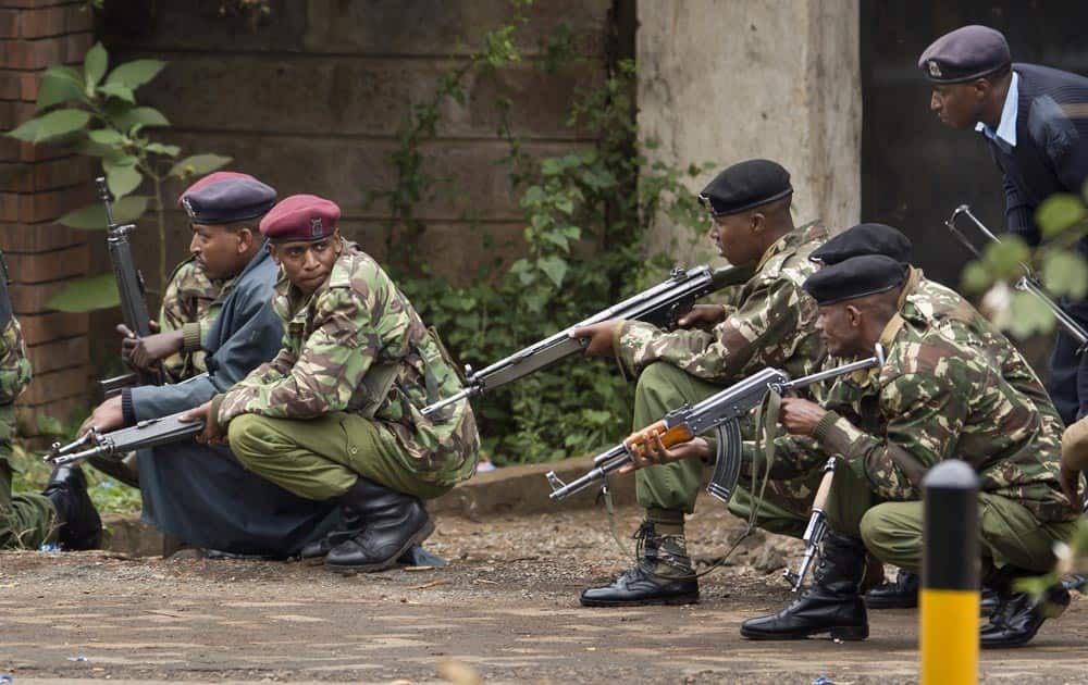 Armed police from the General Service Unit take cover behind a wall during a bout of gunfire, outside the Westgate Mall in Nairobi, Kenya.
