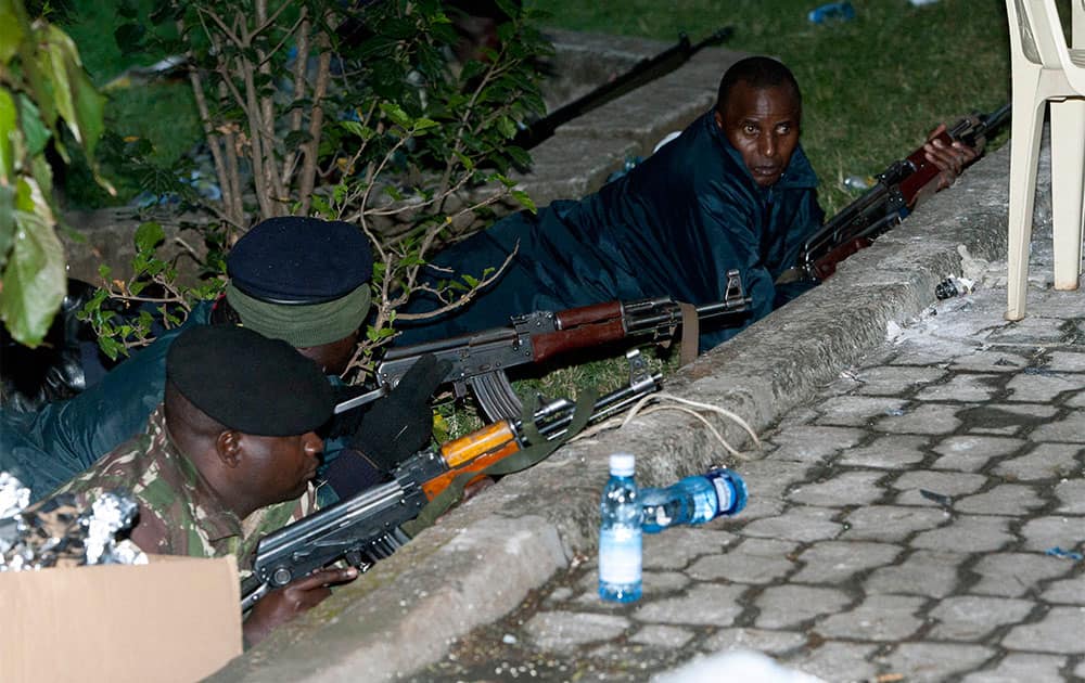 Kenya Security personnel take cover outside the Westgate Mall after firing started inside the mall early Monday morning.