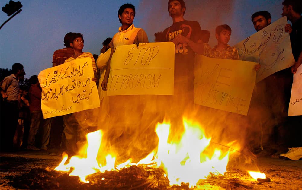 Pakistani Christians hold placards next to burning tires during a protest against a suicide attack on a church in Islamabad, Pakistan.