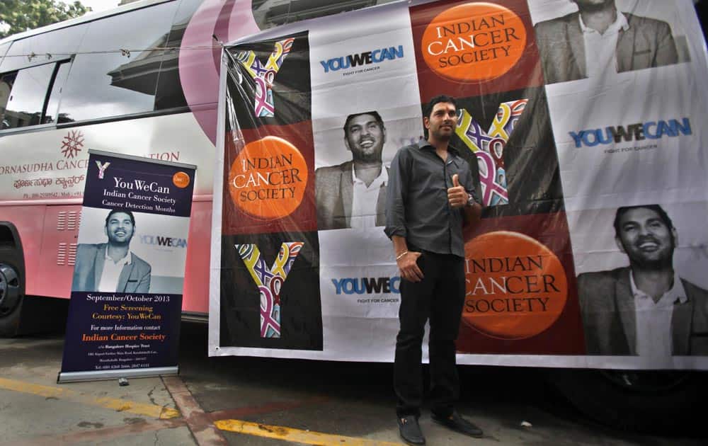 Yuvraj Singh gives a thumbs-up as he poses next to a vehicle fitted with cancer screening equipment in Bangalore.