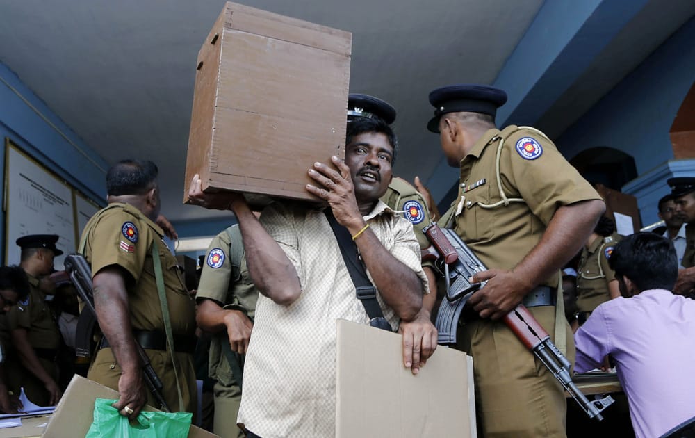 A Sri Lankan election officer carries a ballot box past security officials as he heads off to his polling station on the eve of the northern provincial council election in Jaffna, Sri Lanka.