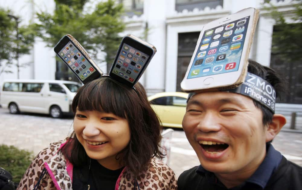 Yui Kashima, left, and Nobuhiko Matsuda wait to purchase an Apple`s new iPhone outside a store in Tokyo.