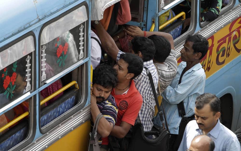 Commuters hang on the door of a crowded bus during a two-day strike called by private bus transport operators in Kolkata.