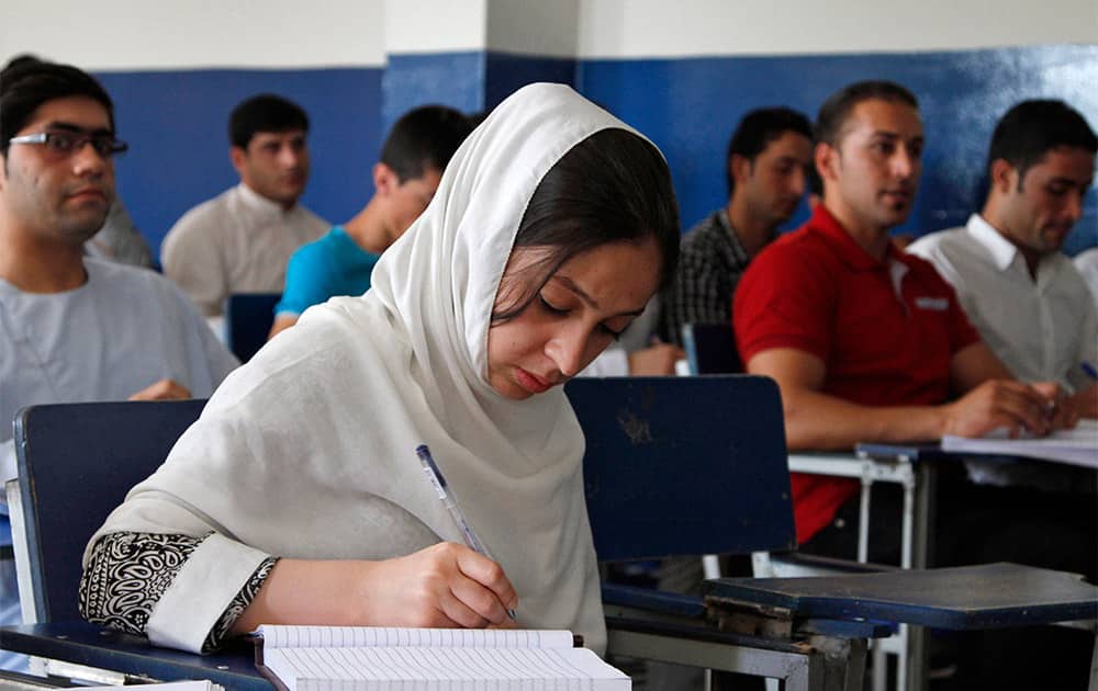 An Afghan sophomore student takes notes in a business administration class at Kardan University in Kabul.