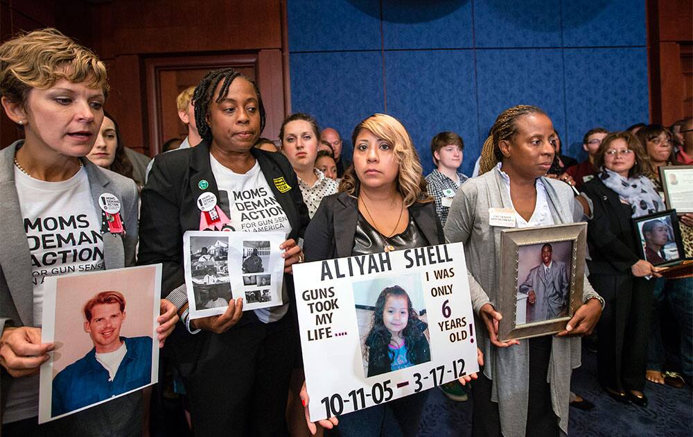 Family members of gun violence victims hold photos of their children as they gather for a news conference to ask Congress for universal background checks legislation for gun purchases, at the Capitol in Washington.