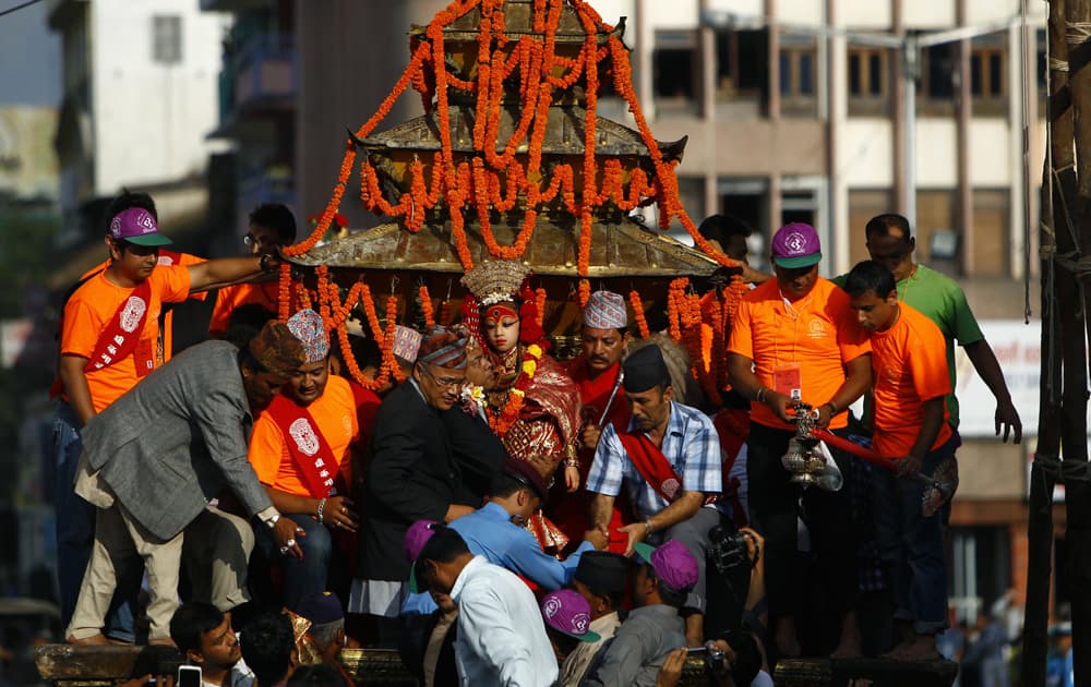 A devotee carries a living goddess locally known as Kumari, to a chariot during the week-long Indra Jatra festival in Katmandu, Nepal.