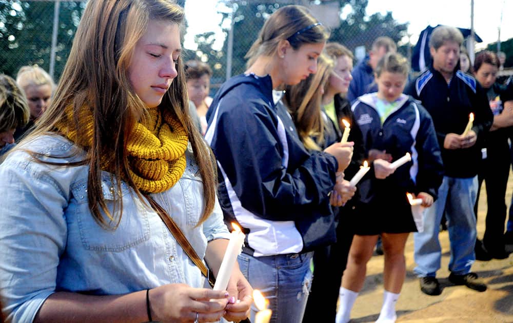 Colette Turner, left, closes her eyes while observing a moment of silence during a candlelight vigil in honor of Richard Michael Ridgell at Jaycee Park in Westminster, Md.