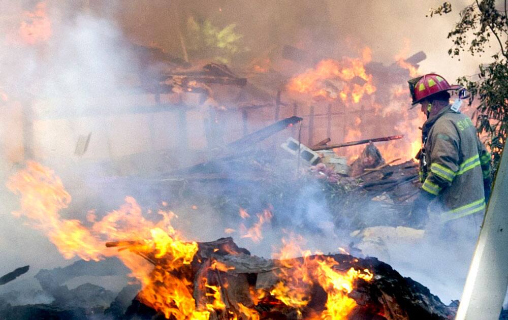 A firefighter walks through the burning rubble of a six-bedroom house on Webbs Hill Road in Stamford, Conn. that exploded.