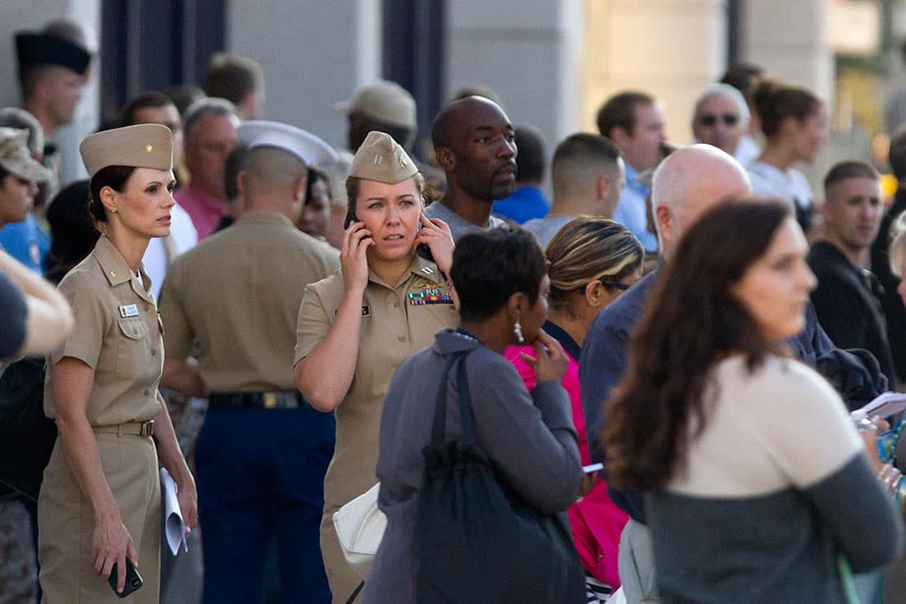 Family and friends wait to greet staff of the Naval Sea Systems Command headquarters as they are bused from the Washington Navy Yard to Nationals Park, in Washington.