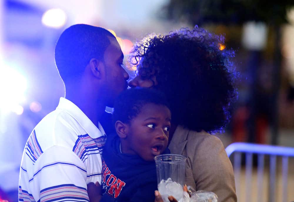 Nii Oti-Ankrah, left, kisses his wife Sally Appiah-Ankrah as he holds their son Eilam Ankrah after she was evacuated from building 197 at the Washington Navy Yard, in Washington.