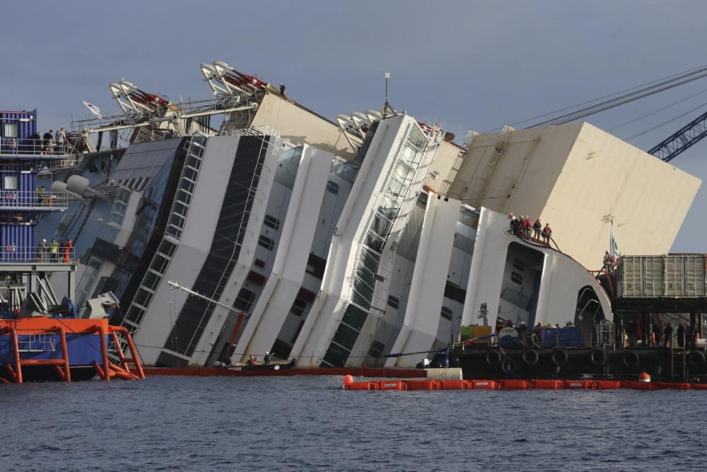 Workers watch the operations on the Costa Concordia ship, lying on its side on the Tuscan Island of Giglio, Italy.