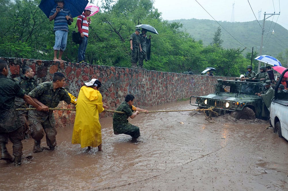 Army soldiers work to try to get their vehicle out of a flooded portion of a road caused by Tropical Storm Manuel in the city of Chilpancingo, Mexico.