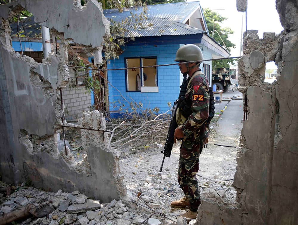 A Government trooper stands next to the destroyed wall following the fighting with Muslim rebels in Zamboanga city, southern Philippines.