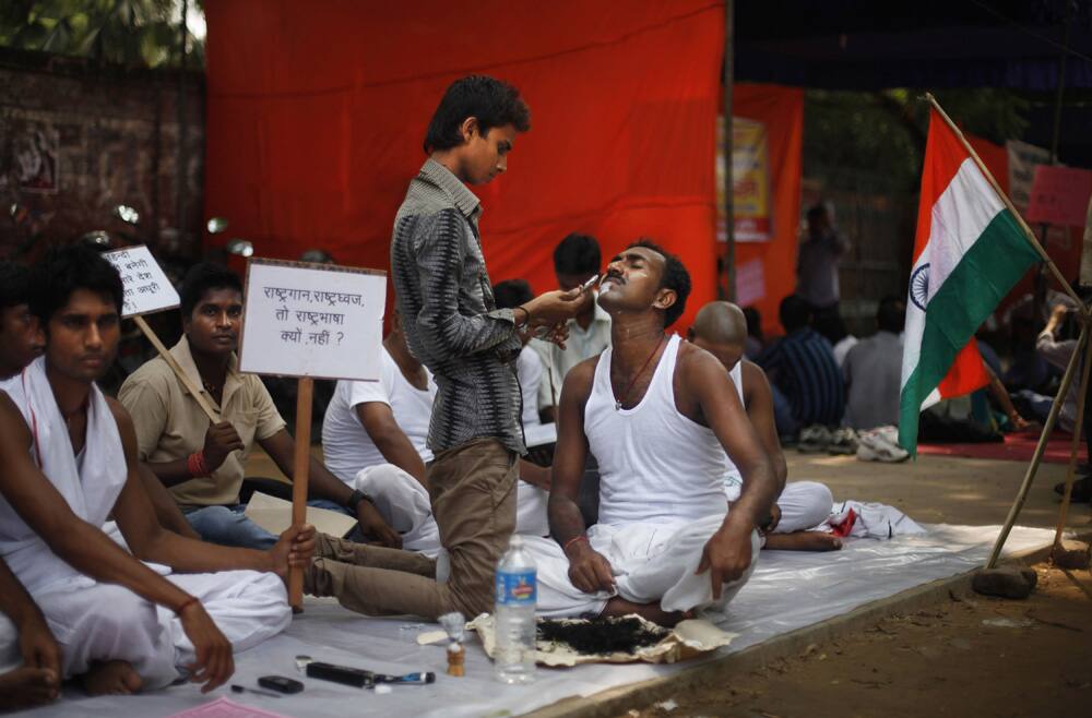 A protester gets his beard and hair shaved as a mark of protest as he joins in demanding that Hindi be declared as national language in New Delhi.