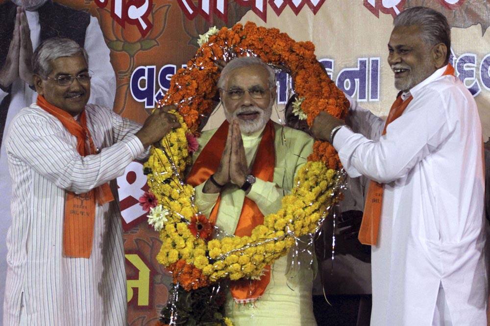 In this Friday, Sept. 13, 2013 photo, Gujarat state chief minister Narendra Modi greets supporters as he accepts a garland offered by leaders of his Bharatiya Janata Party (BJP) upon arrival from Delhi at the airport in Ahmedabad.