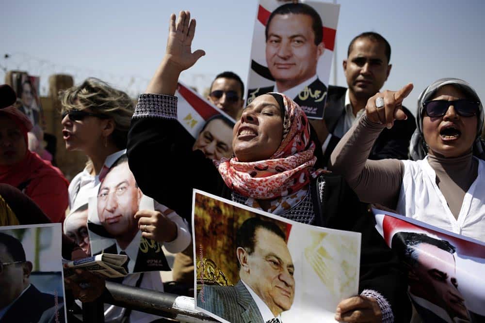 Egyptians carrying photos of ousted president Hosni Mubarak chant slogans against ousted President Mohammed Morsi and the Muslim Brotherhood as they demonstrate their support for Mubarak at a court in Cairo.