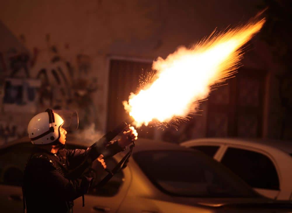 A riot policeman fires tear gas to disperse Bahraini anti-government protesters during a planned march, called by several opposition groups but denied authorization by police, in Mussala, Bahrain.