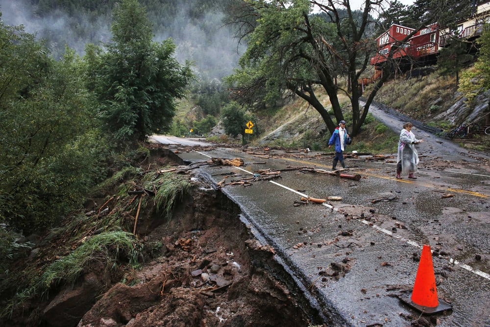 Brother and sister Patrick Tinsley and Mary Kerns walk into Boulder, Colo., from their mountain community Magnolia, where road access is shut off by debris from days of record rain and flooding, at the base of Boulder Canyon, Colo.