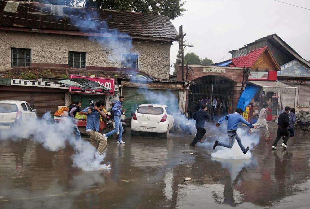 Kashmiris run for cover from tear gas shells thrown at them by the policemen during a protest march in Srinagar.