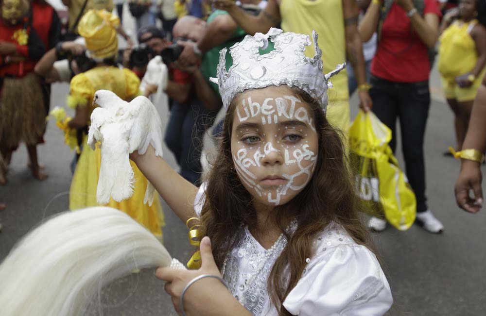 A girl dressed as Obatala, a Saint in the Yoruba religion, holds a live pigeon during a march commemorating the 15th anniversary of the arrest of five Cuban agents in Havana, Cuba.