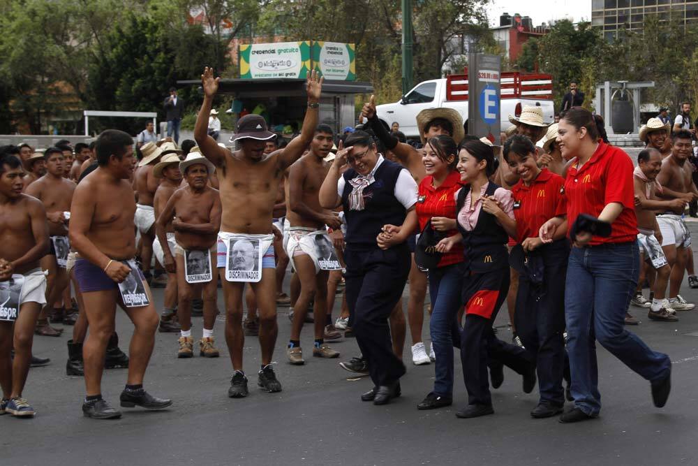 A group of fast-food chain employees laugh as they walk past farmers of the