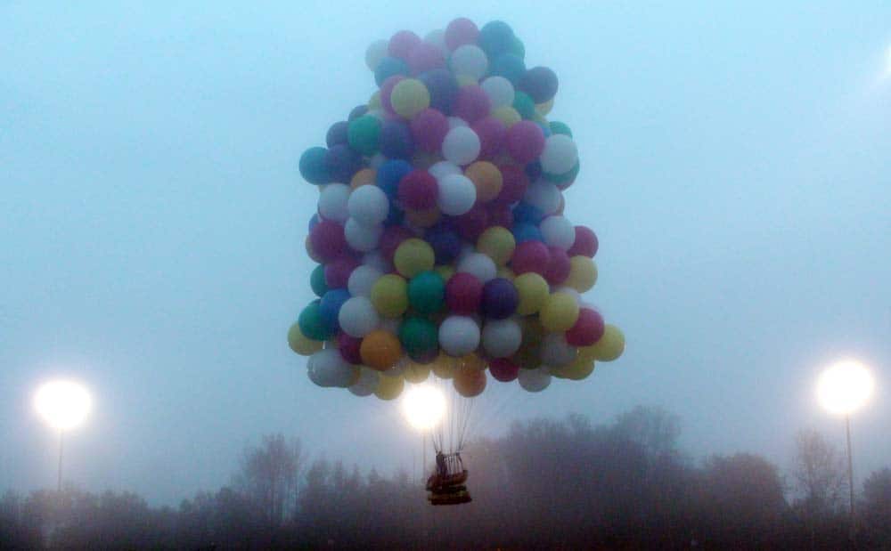 This photo provided by Mark McBreairty, a balloon cluster carrying Jonathan Trappe lifts off from Caribou, Maine.