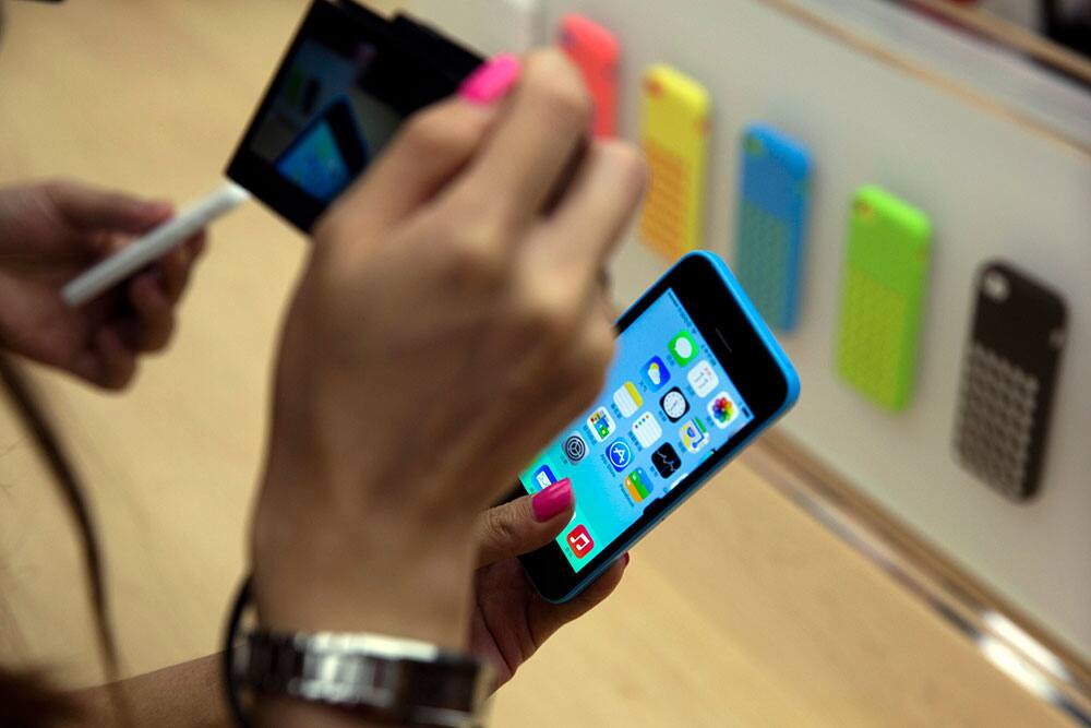 A journalist takes a photo of Apple`s new plastic iPhone during a media event held in Beijing, China.