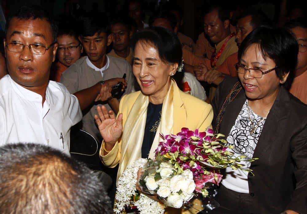 Myanmar`s opposition leader Aung San Suu Kyi, center, arrives at Yangon International Airport for her departure for a human rights forum in Prague.