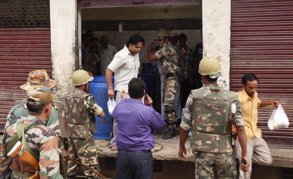 Security person beats a man who arrives to buy milk inside a partially closed shop during a curfew imposed following deadly clashes between Hindus and Muslims at Muzaffarnagar in Uttar Pradesh state.