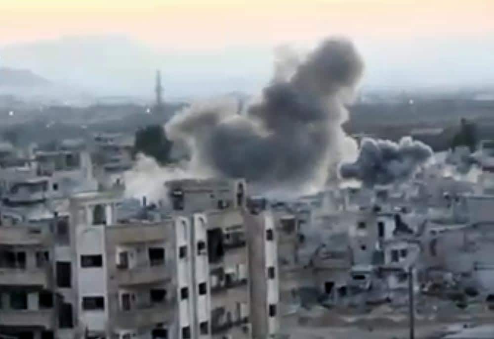 This image taken from video obtained from the Shaam News Network, which has been authenticated based on its contents and other AP reporting, smoke rises from buildings due to heavy artillery shelling in Barzeh, a district of Damascus, Syria.