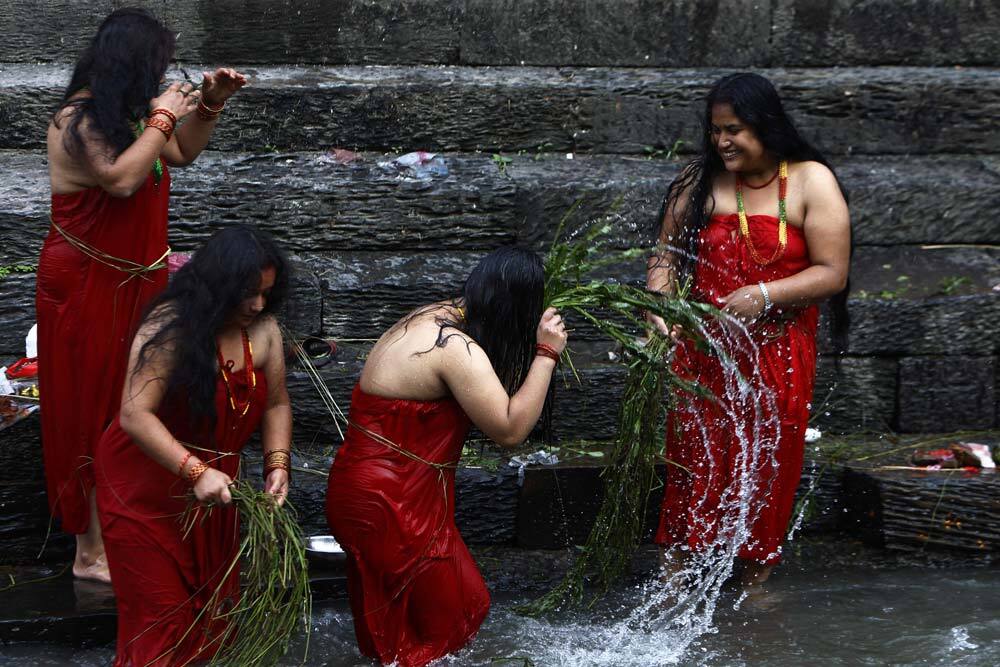 Nepalese Hindu devotees lash themselves with the leaves of the Aghada plant as part of a ritual on the banks of the Bagmati River on Rishi Panchami in Katmandu.