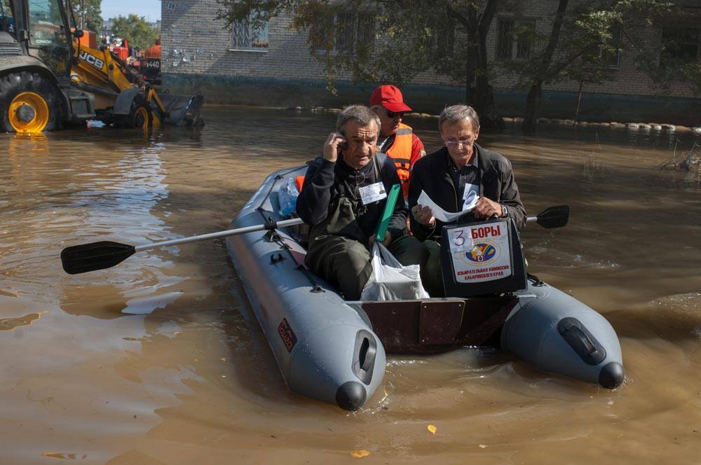 Election officials with a portable polling box travel in a boat by houses to make it possible for local residents who cannot leave their flooded houses to cast their ballots in mayor and region governor elections in Khabarovsk.